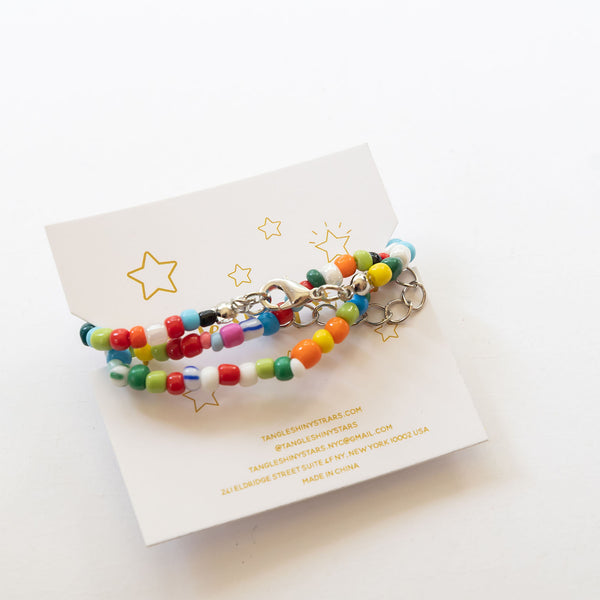 back side of a tag with smiley charm and multi colored bead necklace