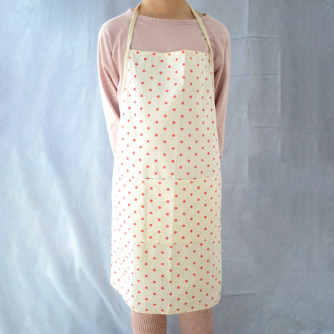 a little boy wearing an apron with red polka dots