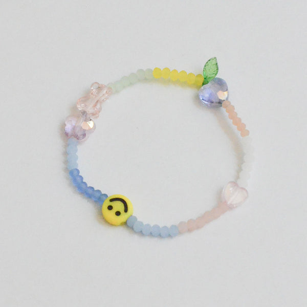 an elastic bracelet of glass beads with charms such as flower, smiley, and heart