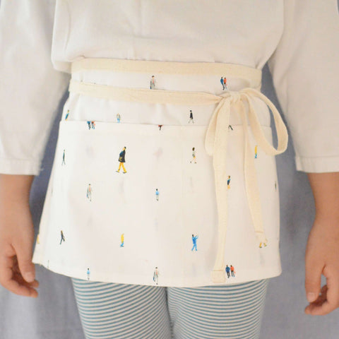 a baby girl wearing a half apron with citizens prints