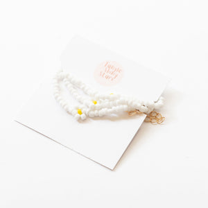 white beaded necklace with flowers with a package